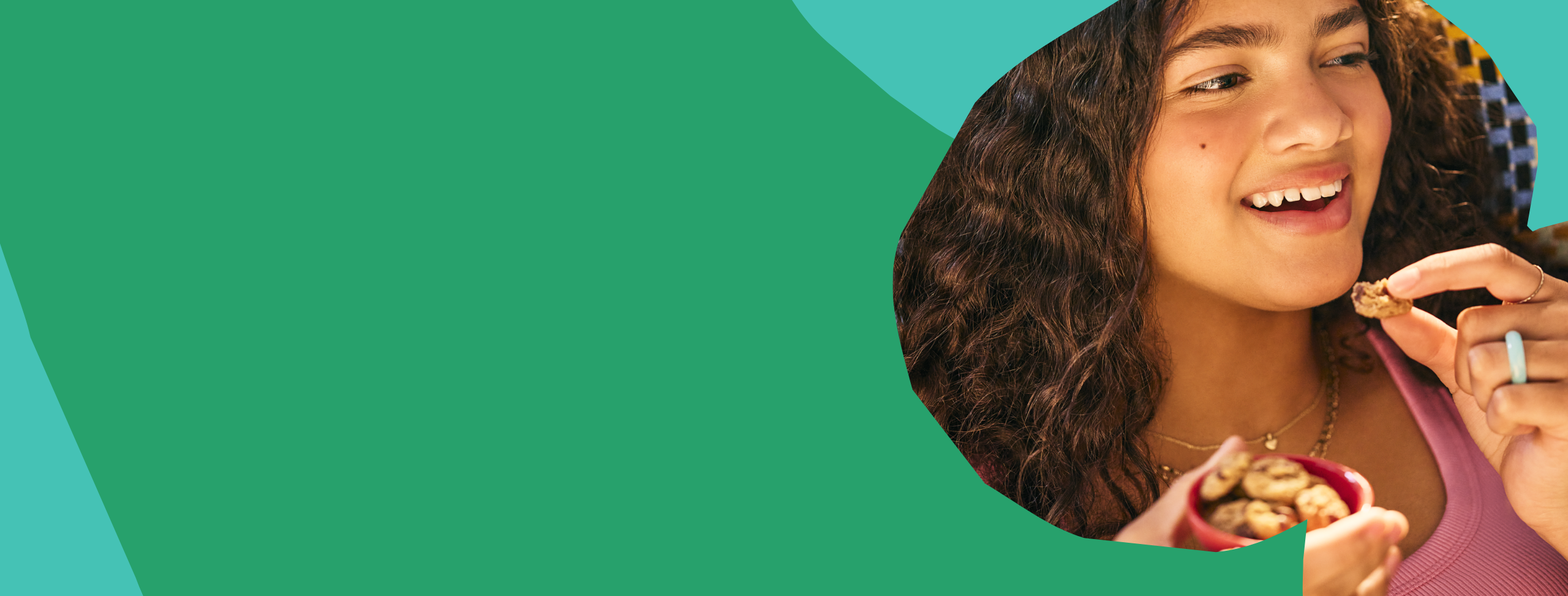 Girl eating MadeGood crunchy cookies on an abstract green and teal background.